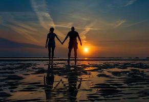 paar Hand in Hand in Richtung Meer in einem Morgengrauen im Spätsommer foto