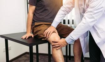 asiatische physiotherapeuten kontrollieren die knie der patienten. foto