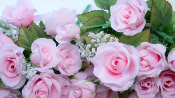 Rosafarbener Rosenstrauß auf einer weißen Oberfläche zur Herstellung von Rahmen und Hintergrund im Konzept des Valentinstags. ein gefälschter Blumenstrauß aus Stoff und Plastik. foto