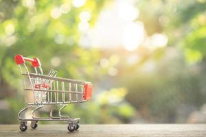 Einkaufskonzept - leerer Einkaufswagen oder Trolley auf braunem Holztisch. Online-Shopping Verbraucher können von zu Hause aus einkaufen und Lieferservice. mit Kopierbereich foto