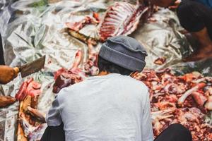 muslimischer mann, der am islamischen tag der eid al-adha-feier fleisch hackt foto