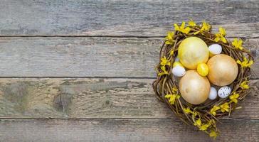 nest mit goldenen und gelben eiern mit blumen auf holzstruktur. Kopieren Sie Platz für Ihren Ostertext foto