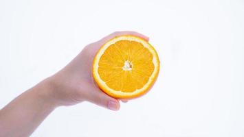 Die Hand einer Frau hält eine reife Orange in ihrer Handfläche. Orangenfrucht in der Hand isoliert auf weißem Hintergrund foto