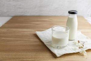 Milchflasche und Glas Milch auf Holztisch foto