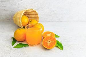 frischer Orangensaft mit Orangenfrucht im Korb foto