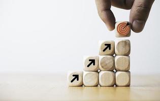 hand, die virtuelle zieltafel und pfeil setzt, die bildschirm auf holzwürfel drucken. geschäftsziel und objektives zielkonzept. foto