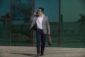 Unternehmer beantwortet Telefonanruf während des Spaziergangs auf der Straße foto