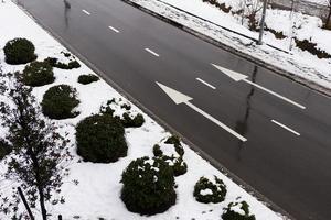 Winterstraße mit zwei parallelen weißen Pfeilen. weiße Pfeile auf einer nassen Asphaltstraße. foto