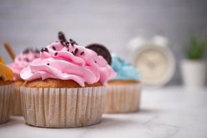 köstliche hausgemachte Cupcakes mit bunter Sahne und Topping mit Süßigkeiten und Schokoladenkeksen. hausgemachtes Herbstferiendessert