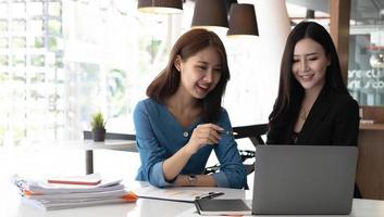 Zwei asiatische Geschäftsfrauen arbeiten zusammen, um die Arbeit im Büro zu erledigen. foto