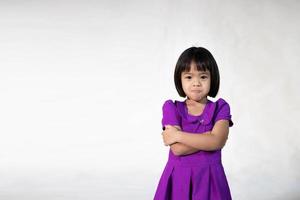 asiatisches süßes mädchenporträt eines fröhlichen kleinen mädchens in grauem t-shirt, das in die kamera schaut und isolierten hintergrund zwinkert. emotionales kaukasisches Mädchen. glückliches Kind. wütend foto