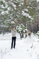 hübscher bräutigam im beigen pullover auf dem hintergrund der verschwommenen braut im verschneiten wald. Winterhochzeit. Platz kopieren foto