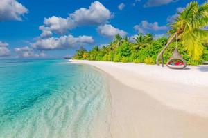 tropischer strandhintergrund als sommerlandschaft mit strandschaukel oder hängematte und weißem sand und ruhigem meer für strandbanner. perfektes strandszenenurlaubs- und sommerferienkonzept. Verbessern Sie den Farbprozess foto