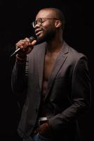 Ein schwarzer Afroamerikaner singt emotional in ein Mikrofon. Nahaufnahme Studioporträt.