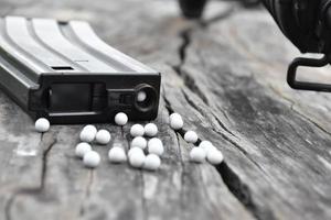 Nahaufnahme von weißen Plastikkugeln aus Airsoft-Pistole oder Bb-Pistole auf Holzboden, weicher und selektiver Fokus auf weiße Kugeln. foto
