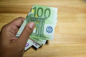 männliche hand, die eurogeldbanknoten hält foto