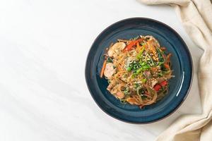 Japchae oder gebratene koreanische Fadennudeln mit Gemüse und Schweinefleisch, garniert mit weißem Sesam foto