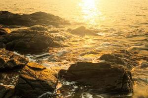 Felsenstrand mit glattem Wasser und Sonnenlicht am Morgen. foto