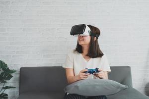 asiatische frau spielt vr-spiel zur unterhaltung zu hause, asiatische frau freut sich im haus im urlaub. glückliche frau, die metaverse vr-technologiekonzept spielt. foto