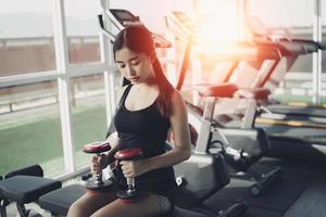 asiatische fitte sportfrau, die im kraftraum im fitnessstudio trainiert. Sport Frau Fitness-Konzept foto