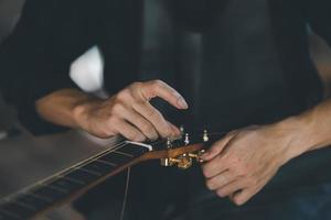 Gitarrenbauer legen Akustikgitarrensaiten an, nachdem sie Akustikgitarren im Concept Guitar Shop, einem Geschäft für handgefertigte Gitarren, hergestellt haben. foto