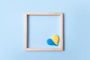 Herzform gelb-blaue Farbe der ukrainischen Flagge in einem quadratischen Holzrahmen mit Kopierraum foto