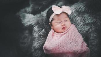 asiatisches Mädchen, das auf dem Bett schläft. Porträt-Baby-Studiobeleuchtung auf Pelzbett. Baby-Familienkonzept foto