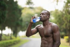 Attraktiver afrikanischer Sportler müde und durstig nach laufendem Training Trinkwasser. Sport Mann Konzept foto