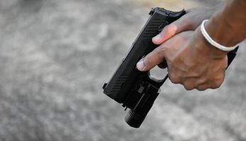 9-mm-Automatikpistole, die Troch unter der Schnauze in der Hand hält, Kopierraum, weicher und selektiver Fokus auf Pistole. foto