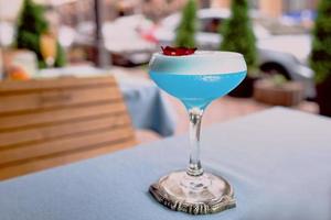 Blauer Cocktail, der auf dem Tisch auf der Terrasse der Bar im Freien steht foto