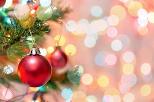 Weihnachtsdekoration. Rote Kugeln, die an Tannenzweigen hängen, Weihnachtsbaumgirlande und Ornamente über abstraktem Bokeh-Hintergrund mit Kopierraum