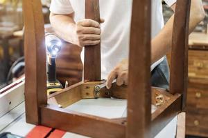 tischlerreparaturstuhl mit schraubenschlüssel in der werkstatt, holzbearbeitungskonzept zur möbelrestaurierung. selektiver Fokus foto