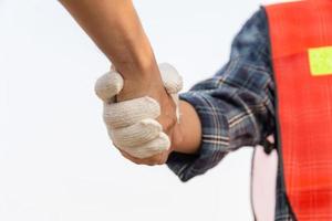 nahaufnahme des ingenieur- und arbeiterhändedrucks mit unscharfem baustellen-, erfolgs- und teamwork-konzept foto