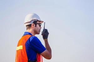 vorarbeiter in helm und sicherheitsweste spricht über bidirektionale funksteuerung, die containerbox von der fracht lädt foto