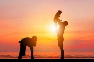 Silhouette von Vater und zwei Kindern, die sich bei Sonnenuntergang amüsieren, glückliches Familienkonzept. foto