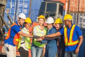 erfolgs- und glücksteamarbeitskonzept, geschäftsleutegruppe, ingenieur- und arbeiterteam, die hände mit unscharfem frachtcontainerhintergrund verbinden foto