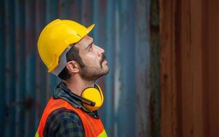 ingenieurmann in helm und sicherheitsweste, der baustelle, bauarbeiter mit schützenden kopfhörern aussieht foto