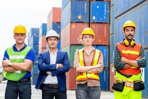 Erfolgsteamarbeitskonzept, Geschäftsleute, Ingenieur und Arbeiterteam, die mit gekreuzten Armen als Zeichen des Erfolgs stehen, verschwommen den Hintergrund der Containerbox foto