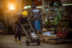 ingenieur wird inspiziert und überprüft den produktionsprozess auf der werkstation, der einen schraubendreher hält, indem er eine schutzmaske trägt, um sich vor verschmutzung und viren in der fabrik zu schützen. foto