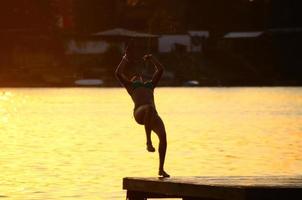 Frau im Bikini springt rückwärts in den See foto