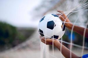 das zugeschnittene Bild von Sportlern, die den Ball und das Fußballfeld fangen. Sport-Image-Konzept. foto