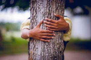 das Bild hat die Bäume junger Männer umarmt, die die Natur lieben. natürliches Pflegekonzept foto