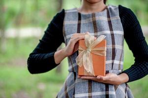 Hand und orangefarbene Geschenkboxen geben Sie Ihren Lieben. Geschenkideen foto
