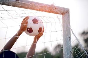 das zugeschnittene Bild von Sportlern, die den Ball und das Fußballfeld fangen. Sport-Image-Konzept. foto