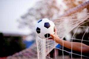 das zugeschnittene Bild von Sportlern, die den Ball und das Fußballfeld fangen. Sport-Image-Konzept. foto