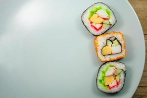 Sushi-Maki auf einem Teller über Holztisch foto