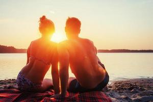 romantisches Paar am Strand bei farbenfrohem Sonnenuntergang foto
