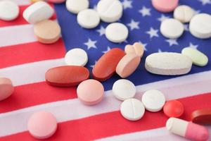 Weiße medizinische Pillen, die auf der amerikanischen Flagge verschüttet werden foto