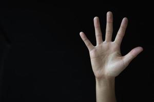 Frauenhandfläche auf schwarzem Hintergrund. misshandelte Frau. stoppen Sie Gewalt und Missbrauch von Frauen. Internationaler Frauentag. foto