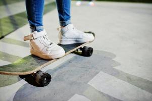 Beine eines urbanen Mädchens im Teenageralter auf Skateboard im Skatepark am Abend. foto